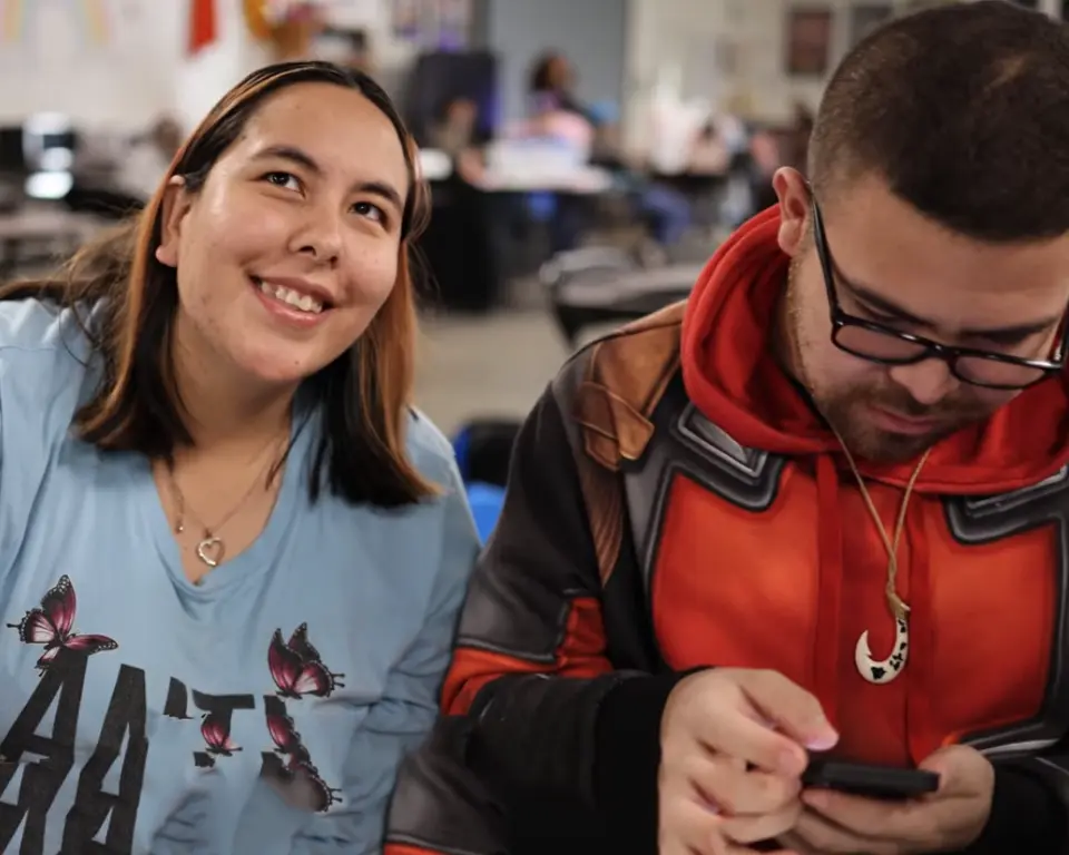 Photo of two individuals, one smiling and the other lookng at his phone at club 194