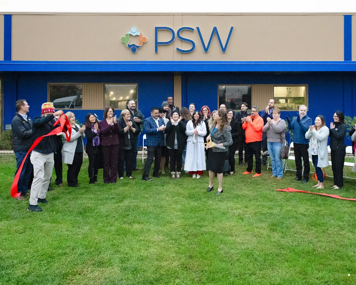 Photo of our community members and business partners standing outside of PSW after the ribbion cuttting realing the new PSW Logo.